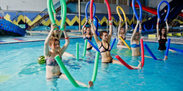 Fitness group of girls doing aerobical excercises in swimming po