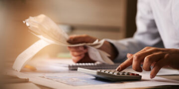 Close-up of business accountant using calculator while working i